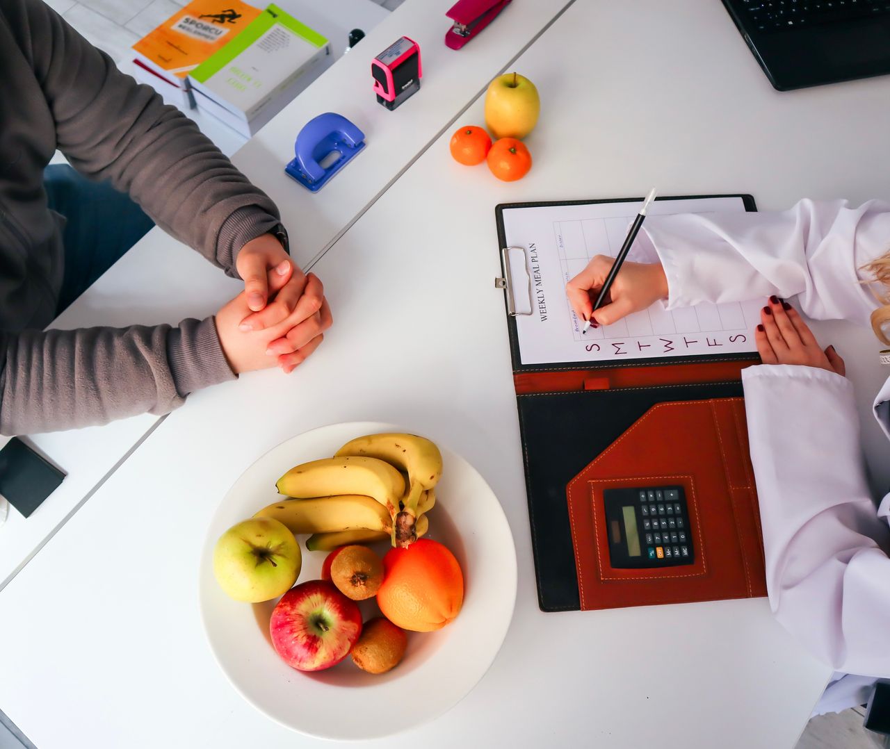 Home Top view of a dietitian planning a healthy diet with fresh fruits on the table, focusing on health and nutrition.