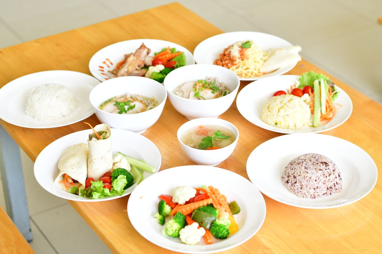 Services A variety of healthy dishes including rice, soup, and vegetables served on a wooden table.