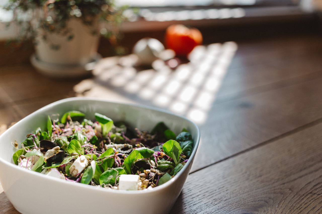 Home A vibrant and healthy bowl of tofu salad with fresh greens, captured in natural light on a wooden table.