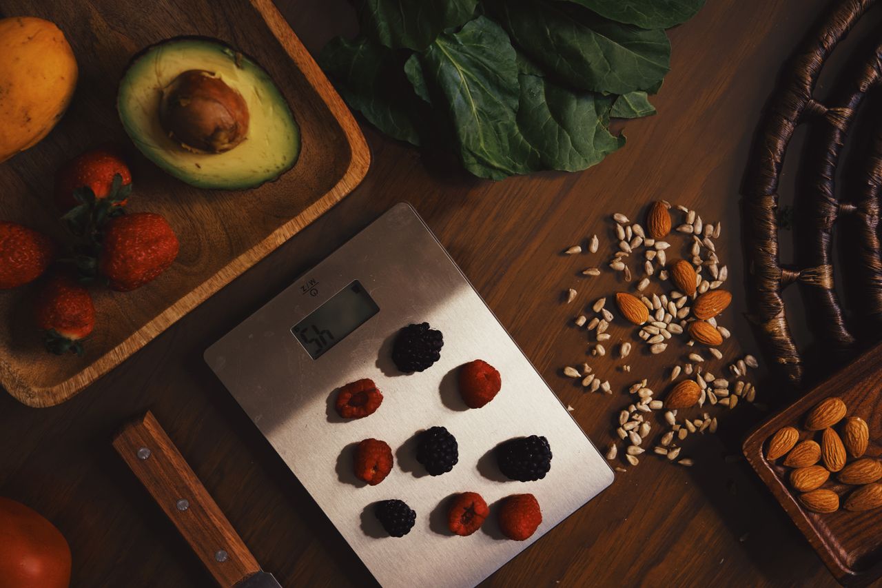 Home Top view of composed raw almond with seeds and avocado on table with berries on scales for cooking healthy dish